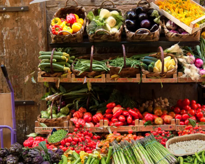 A vibrant display of fresh vegetables and fruits arranged in baskets at a market stall.
