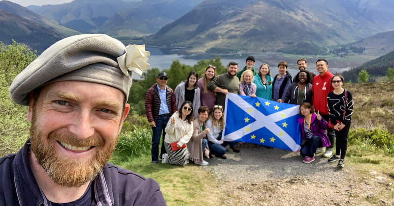 a group on a Rabbie's tour in Scotland with a Scottish flag