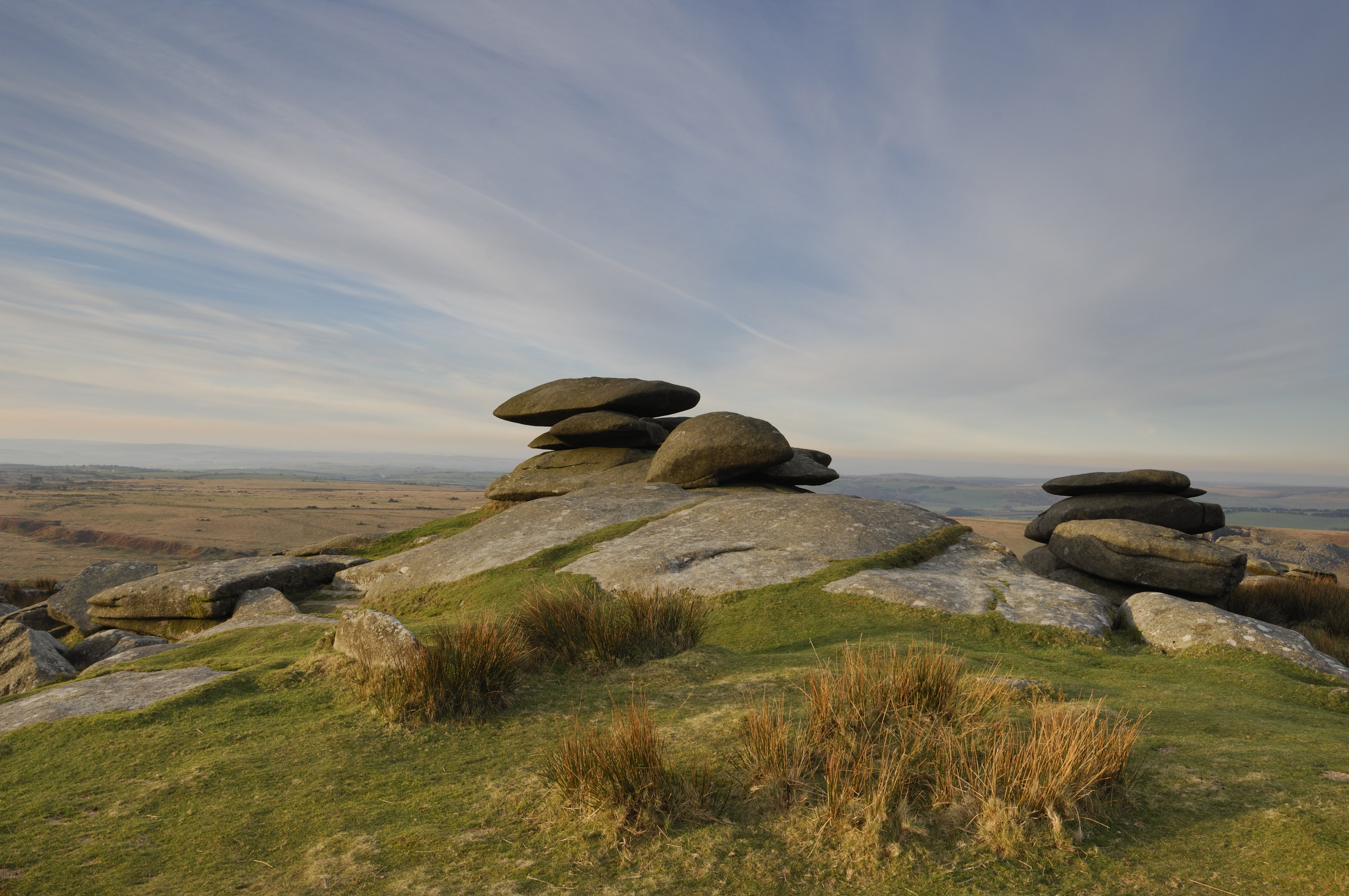 bodmin moor landscape with blue cloudy sky above and a formation of stones in the fore ground