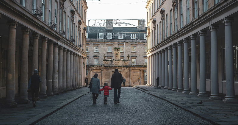 A family holding hands walking among old buildings