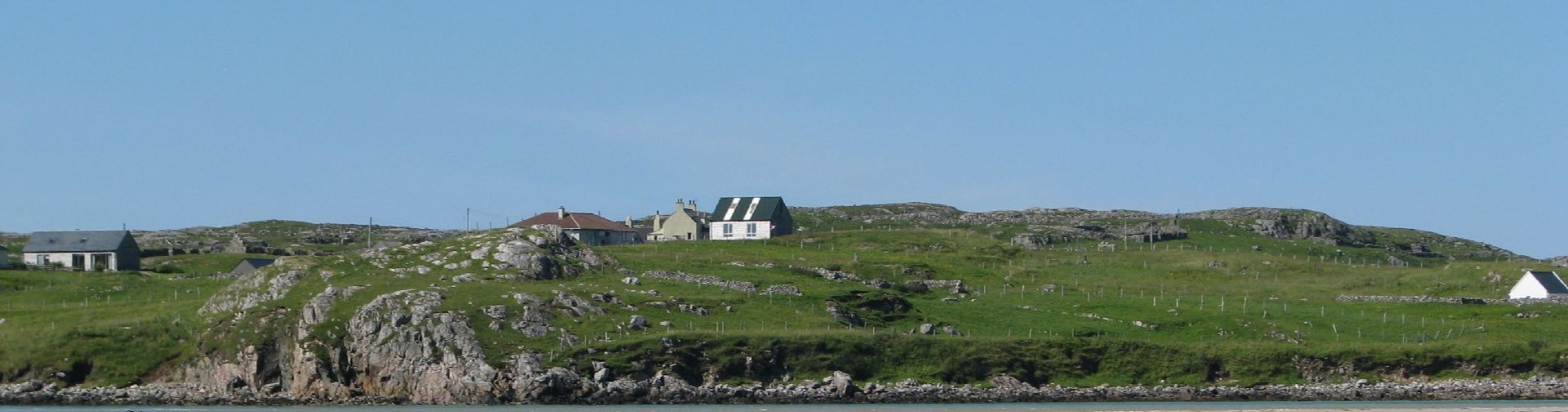 Small houses set in a green coastal landscape. 