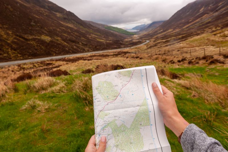 A person holding a map in front of a valley