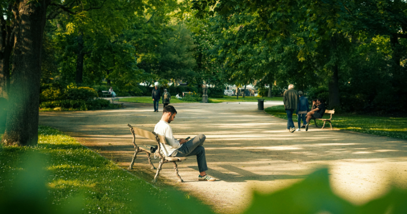 a man sitting on a bench in a park