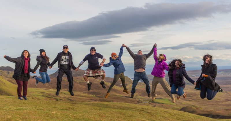 A group of people jumping into the air in a beautiful landscape