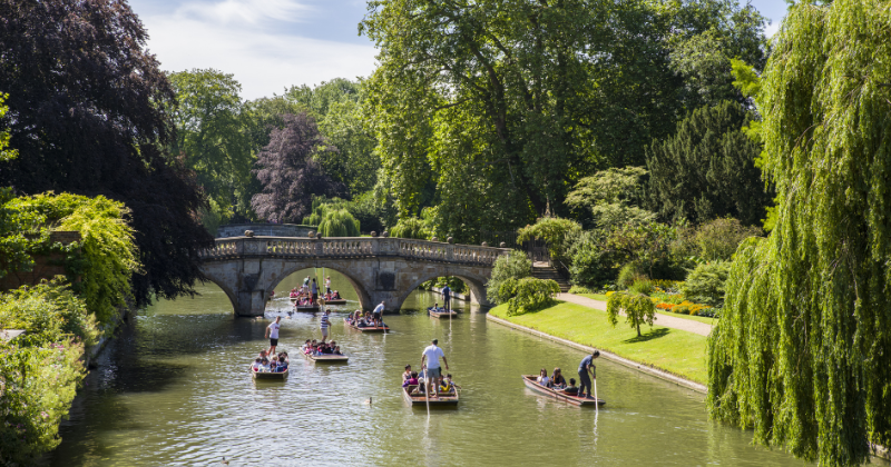 Small boats going down a river with a bridge