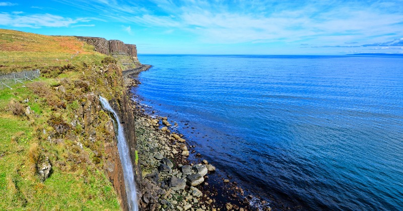 A waterfall cascading from a cliff into the ocean