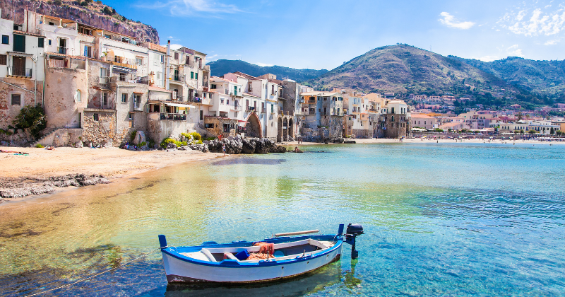 a boat in blue water outside a seaside village