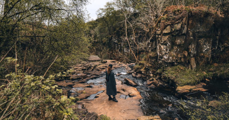 A woman standing at the top of a waterfall