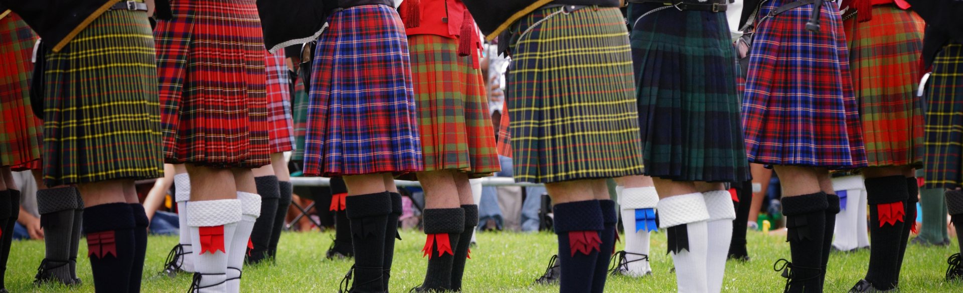 The legs of proud members of Scottish clans wearing kilts in a row