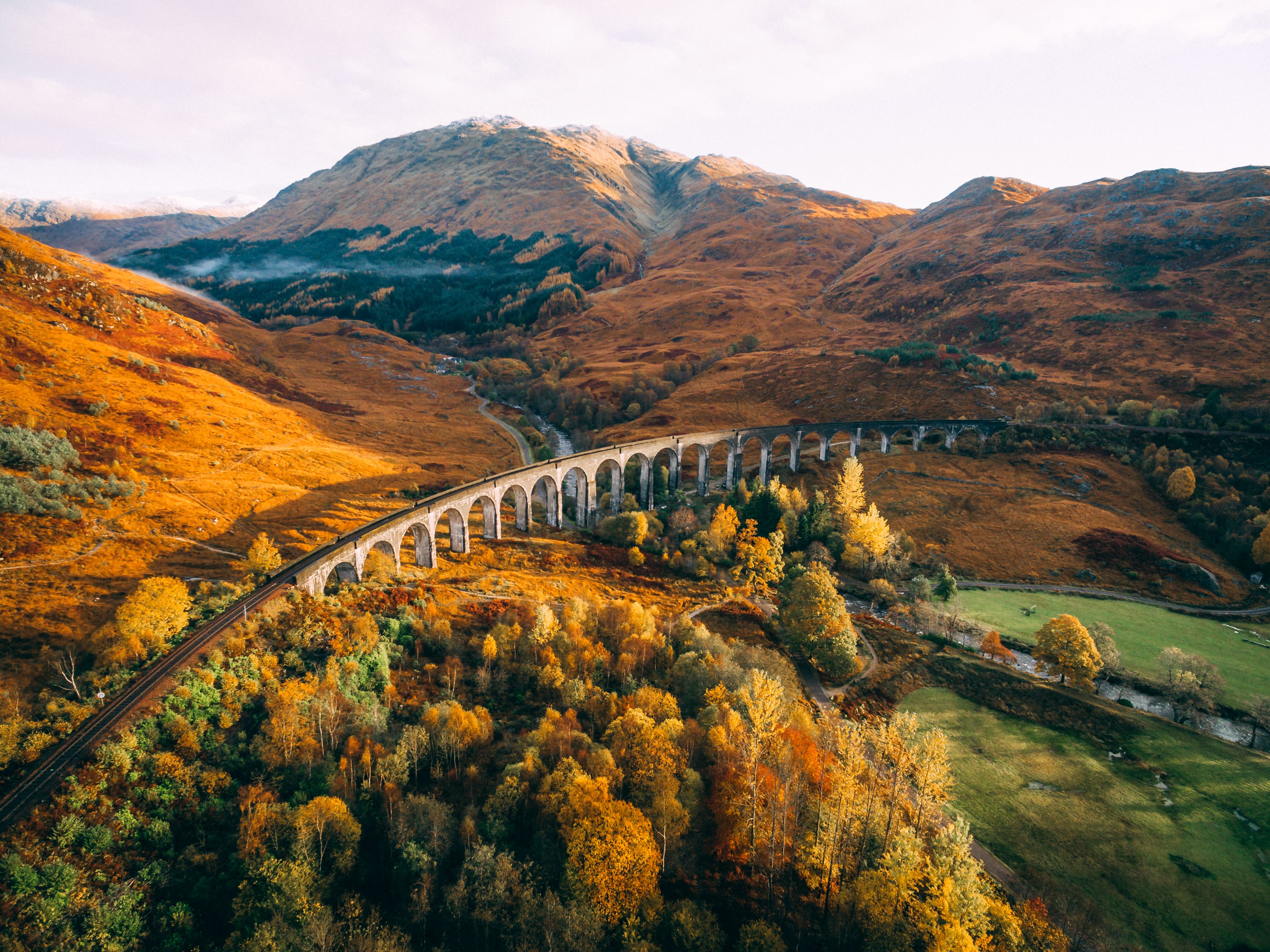 glenfinnan viaduct train track bridge with autumn landscape in the background