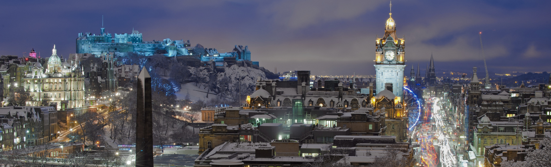 A view of the city of Edinburgh at night with lights and Christmas markets