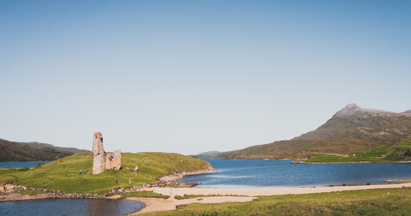 A white sandy beach and blue water, with a castle on a small island