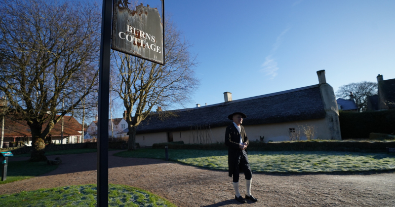 a man standing outside a cottage