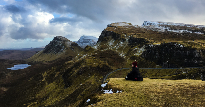 A girl sitting on a cliff's edge with an incredible view