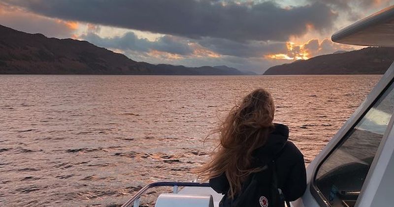 a woman admiring Loch Ness at dusk from aboard a ferry