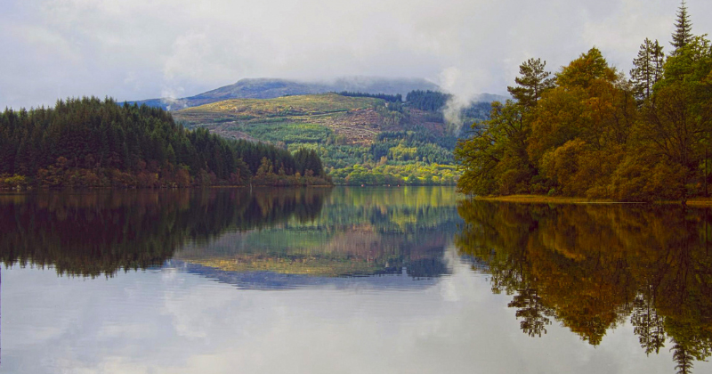 A quiet loch surrounded by trees and mountains