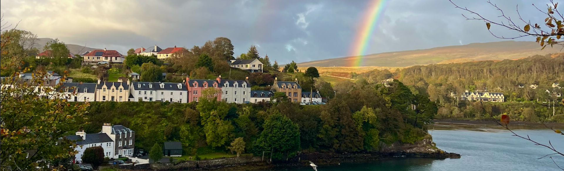 A row of coloured houses with a rainbow overtop