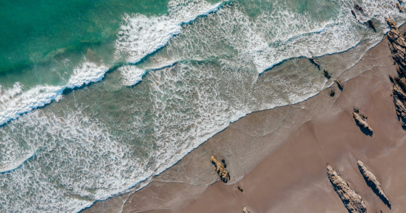 A birds eye view of a sandy beach and rocks