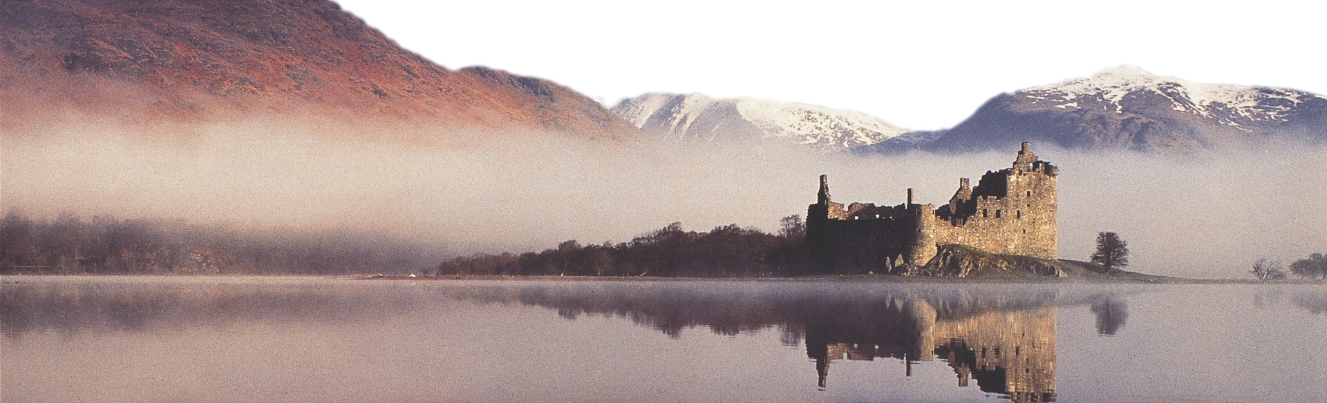 A castle on a loch with mist around it